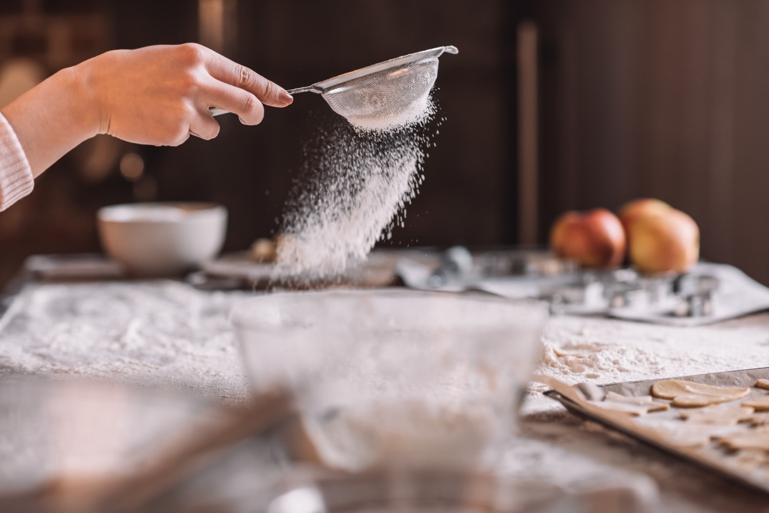 Flour being sifted over a baking counter