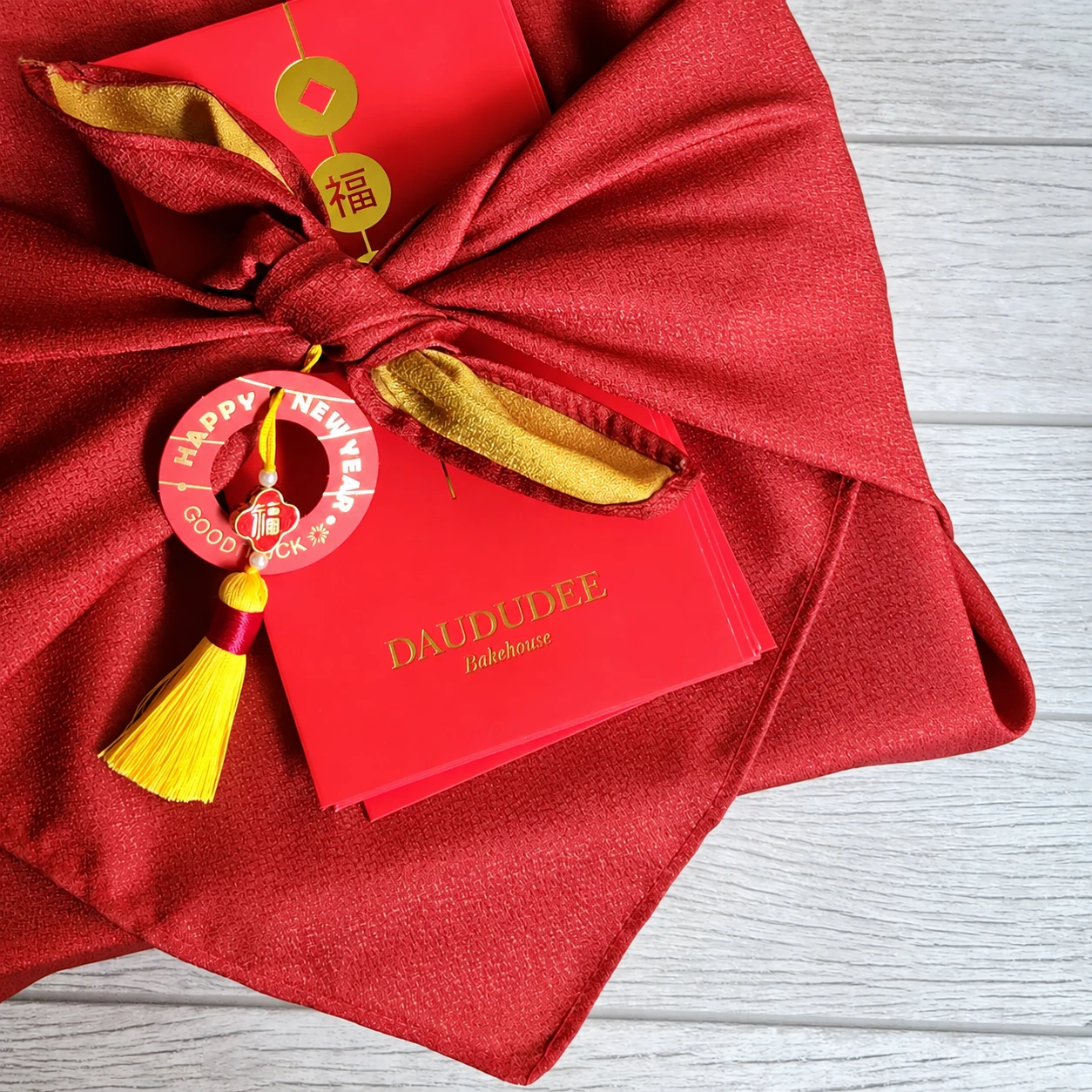Red fabric-wrapped gift box with festive tassel and red packet